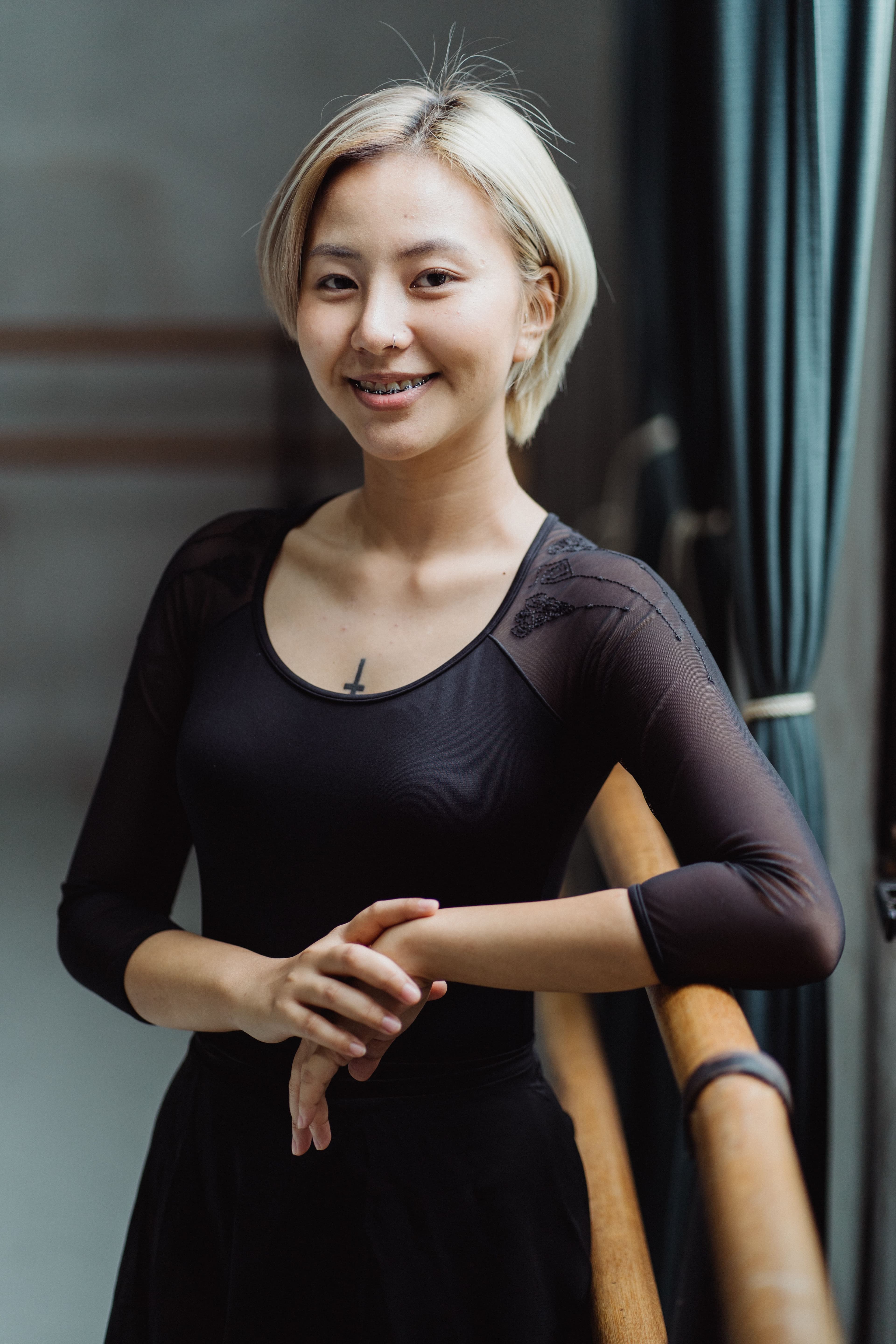 A dancer poses gracefully at the barre in a bright, sunlit studio